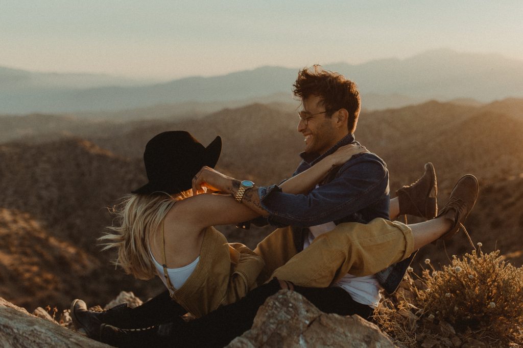 Couple playfully pose for their engagement photos during sunset overlooking the valley in Joshua Tree California