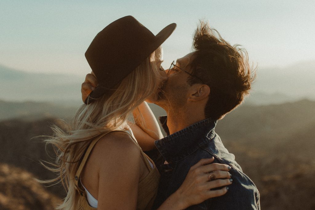 Couple embraces for their engagement photos during sunset overlooking the valley in Joshua Tree California