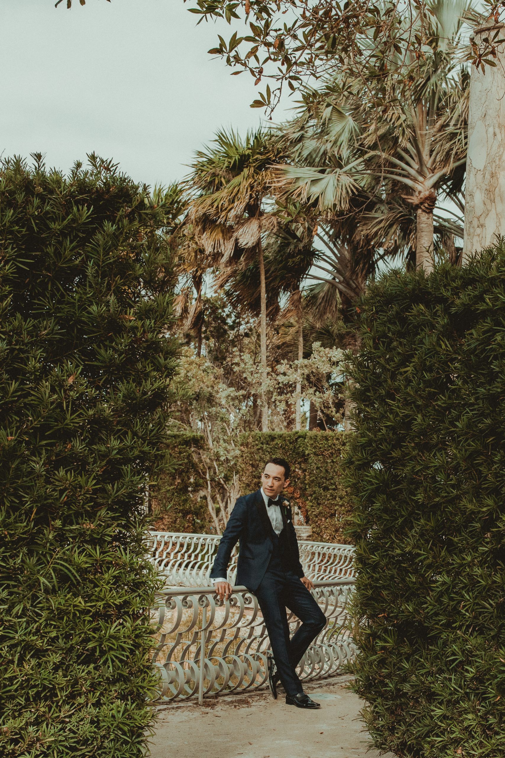 Groom portrait leaning against a garden railing at Vizcaya Miami